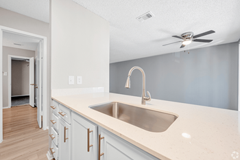 An empty kitchen with a sink and a ceiling fan